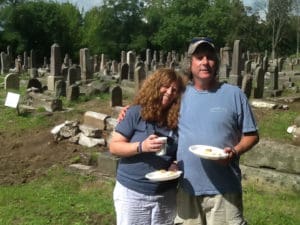 A man and woman holding plates in front of some grave markers.