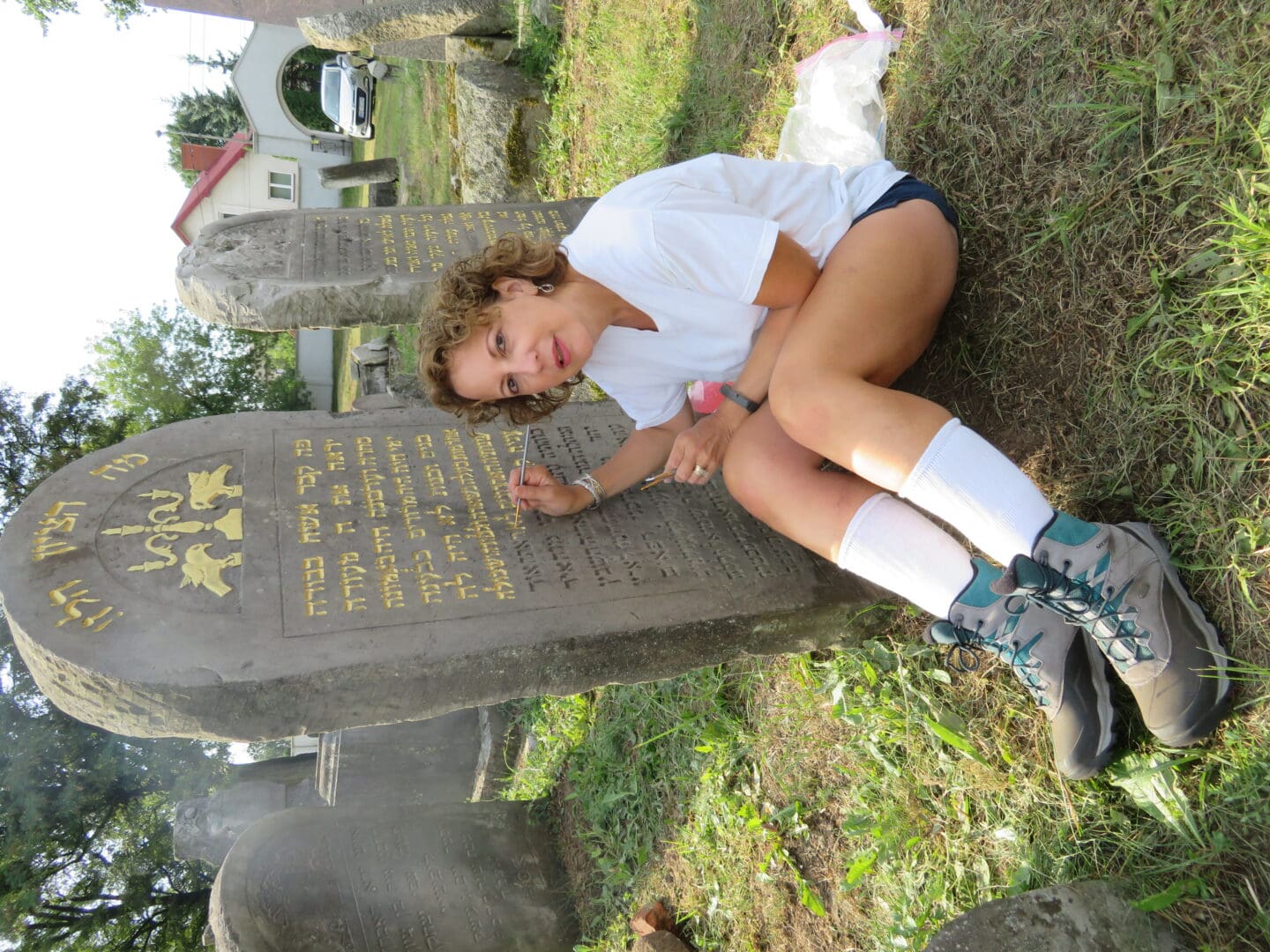 A woman sitting on the ground in front of a grave.